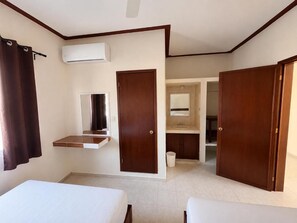 A hotel room with a bed, a small desk, an air conditioning unit, a mirror, and a bathroom with a sink and mirror. - Microhotel Ciudad del Carmen (Ciudad del Carmen)