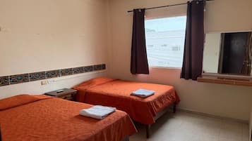 A hotel room with two beds, a ceiling fan, an air conditioning unit, and a window with curtains.