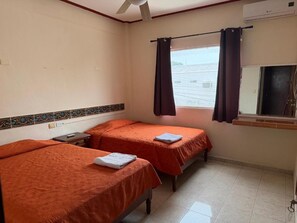 A hotel room with two beds, a ceiling fan, an air conditioning unit, and a window with curtains. - Microhotel Ciudad del Carmen (Ciudad del Carmen)
