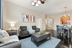 Ein modernes Wohnzimmer mit einer Couch, einem Couchtisch und einem Essbereich mit Stühlen und Tisch.