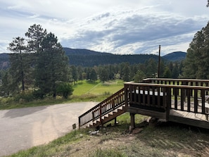 A wooden staircase leading to a deck overlooking a road and a grassy area with trees. - Peaceful Mountain Retreat Near Durango with Beautiful Nature Views (Bayfield)