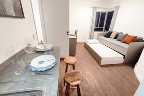 A compact living space with a dining area, a sofa bed, and a small table. - Apart Beautiful Sky, Feirinha Liberdade São Paulo (São Paulo)