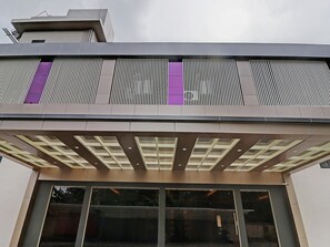 A modern building with a flat roof, large windows, and a section with vertical slats.