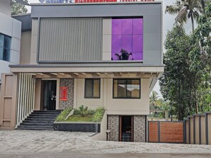 A modern two-story building with a prominent entrance, a staircase leading to the upper level, and a gated driveway.