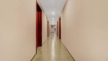 Un pasillo largo y estrecho con suelo de baldosas y puertas de madera a ambos lados.