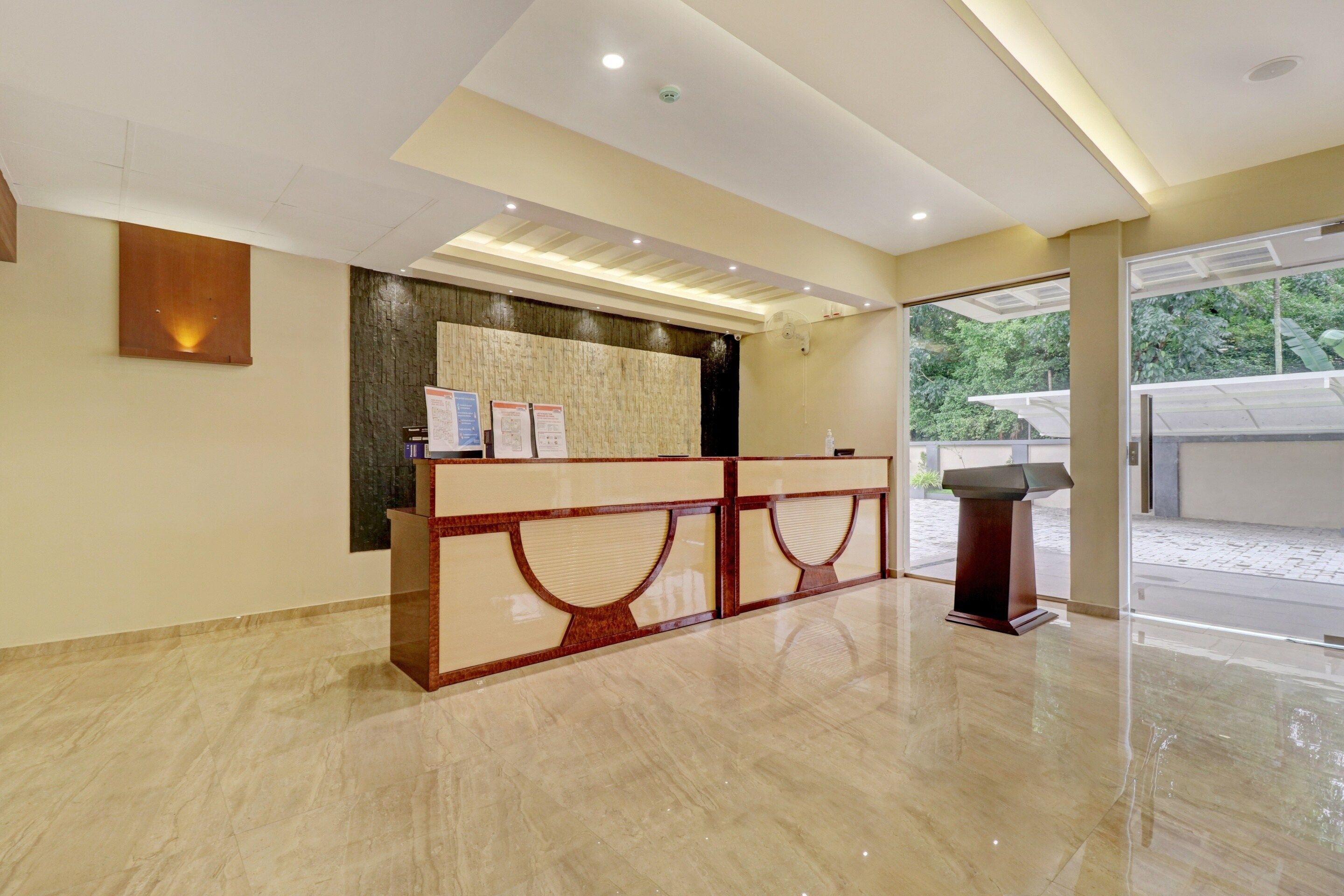 A reception area with a marble floor, a reception desk, and a view of the outdoors through a glass door.