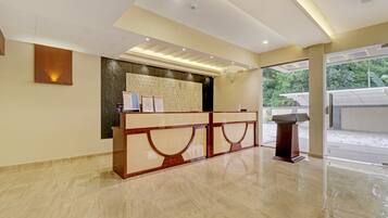 A reception area with a marble floor, a reception desk, and a view of the outdoors through a glass door.