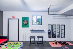 A room with a dartboard, a window with a view, a foosball table, a treadmill, and a mirror. - Family Retreat /Heated Pool/Billard/FirePit 12pp (Hollywood)