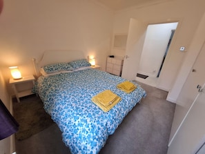A bedroom with a bed, bedside lamps, a dresser, and a mirror. - Spacious, quiet 2 bedroom garden flat sleeps 4 (Coatbridge)