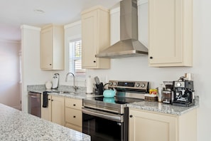 A modern kitchen with light-colored cabinets, stainless steel appliances, and a granite countertop. - 13 mins to Campbell University Boho Retreat (Angier)