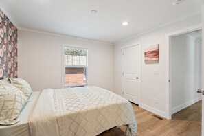 A bedroom with a bed, a window with blinds, a door, and a wall-mounted artwork. - 13 mins to Campbell University Boho Retreat (Angier)