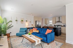 A modern living room with a blue sofa, a wooden coffee table, and a patterned rug. - 13 mins to Campbell University Boho Retreat (Angier)