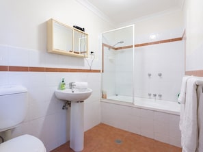 A bathroom with a toilet, sink, mirror, shower, and bathtub. - Bondi Beach Studio | 2 Min Walk to Sand, Sleeps 4, Queen Bed & Sofa Bed (Bondi Beach)