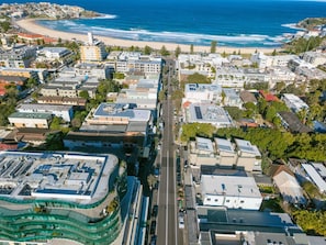 An aerial view of a coastal city with a central road, buildings, and a beach. - Bondi Beach Studio | 2 Min Walk to Sand, Sleeps 4, Queen Bed & Sofa Bed (Bondi Beach)