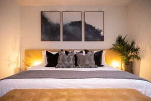 Ein Schlafzimmer mit einem Bett, Kissen, einer Nachttischlampe und einer Wandpflanze.
