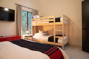 A bunk bed room with a TV on the wall, a desk, and a window with curtains. - Hood Hideaway: Dog-Friendly Mt. Hood Cabin, Private Hot Tub, Sleeps 8 (Rhododendron)