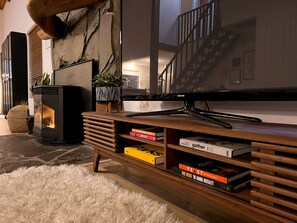 A cozy living room with a fireplace, a television, and a bookshelf with books. - Hood Hideaway: Dog-Friendly Mt. Hood Cabin, Private Hot Tub, Sleeps 8 (Rhododendron)