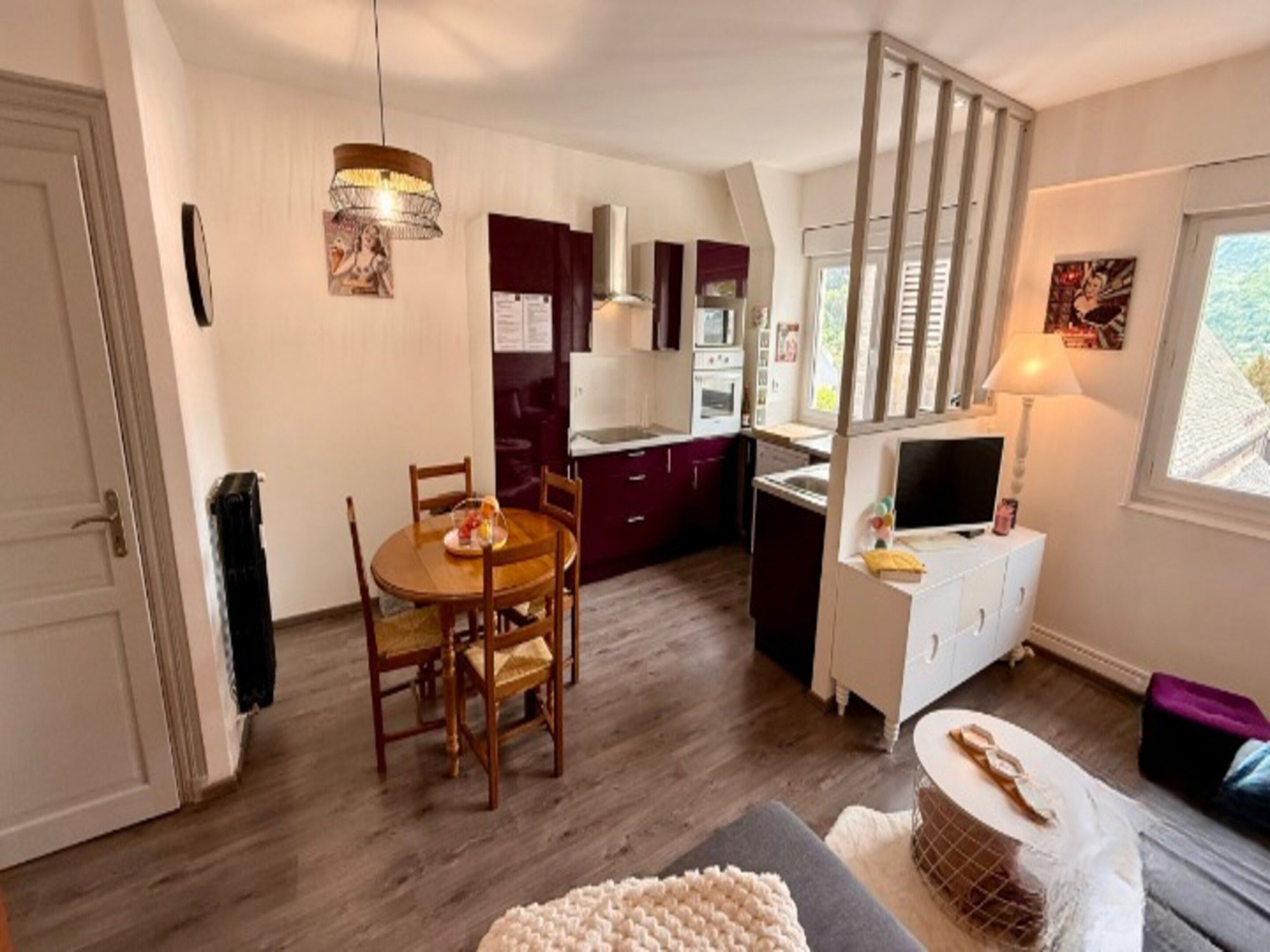 A compact living space with a dining area, kitchenette, and a television.