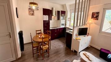 A compact living space with a dining area, kitchenette, and a television.