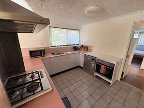 A compact kitchen with a gas stove, microwave, sink, and a small oven. - Manly Bayside Retreat 3BR 2BA Free Parking (Manly)