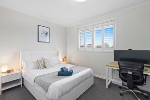 A bedroom with a bed, bedside tables, a desk with a chair, a window with blinds, and a framed picture on the wall. - Quiet Sunlit Sanctuary, St Kilda | WiFi, Parking (Saint Kilda East)