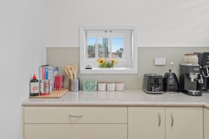 A kitchen with a window, a coffee machine, a toaster, and various kitchen items on the counter. - Quiet Sunlit Sanctuary, St Kilda | WiFi, Parking (Saint Kilda East)