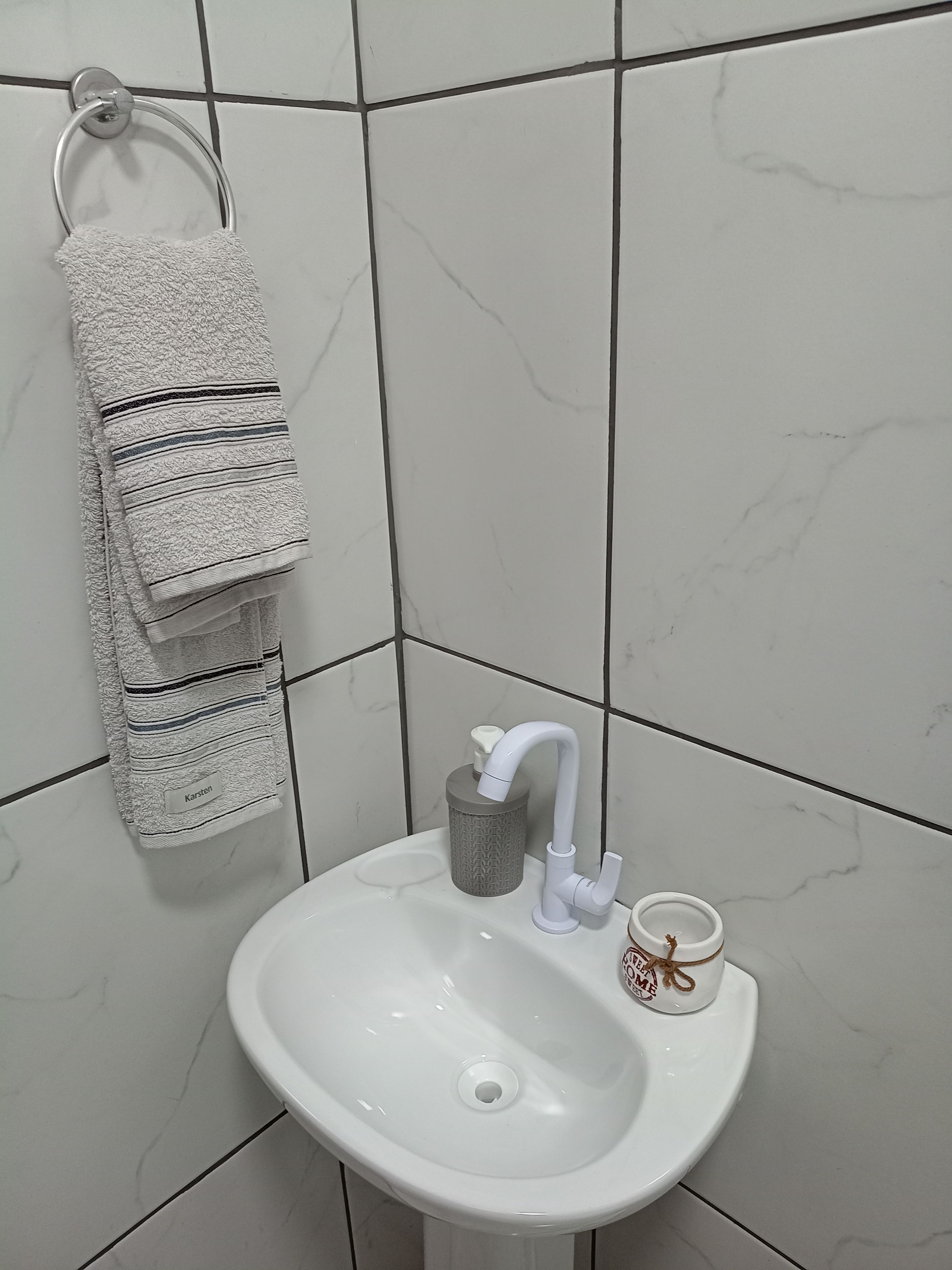 Un lavandino in bagno con un porta asciugamani che regge un asciugamano piegato e una tazza.