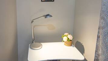 Et hjørnekontor med skrivebord, stol, lampe og et billede i ramme på væggen.