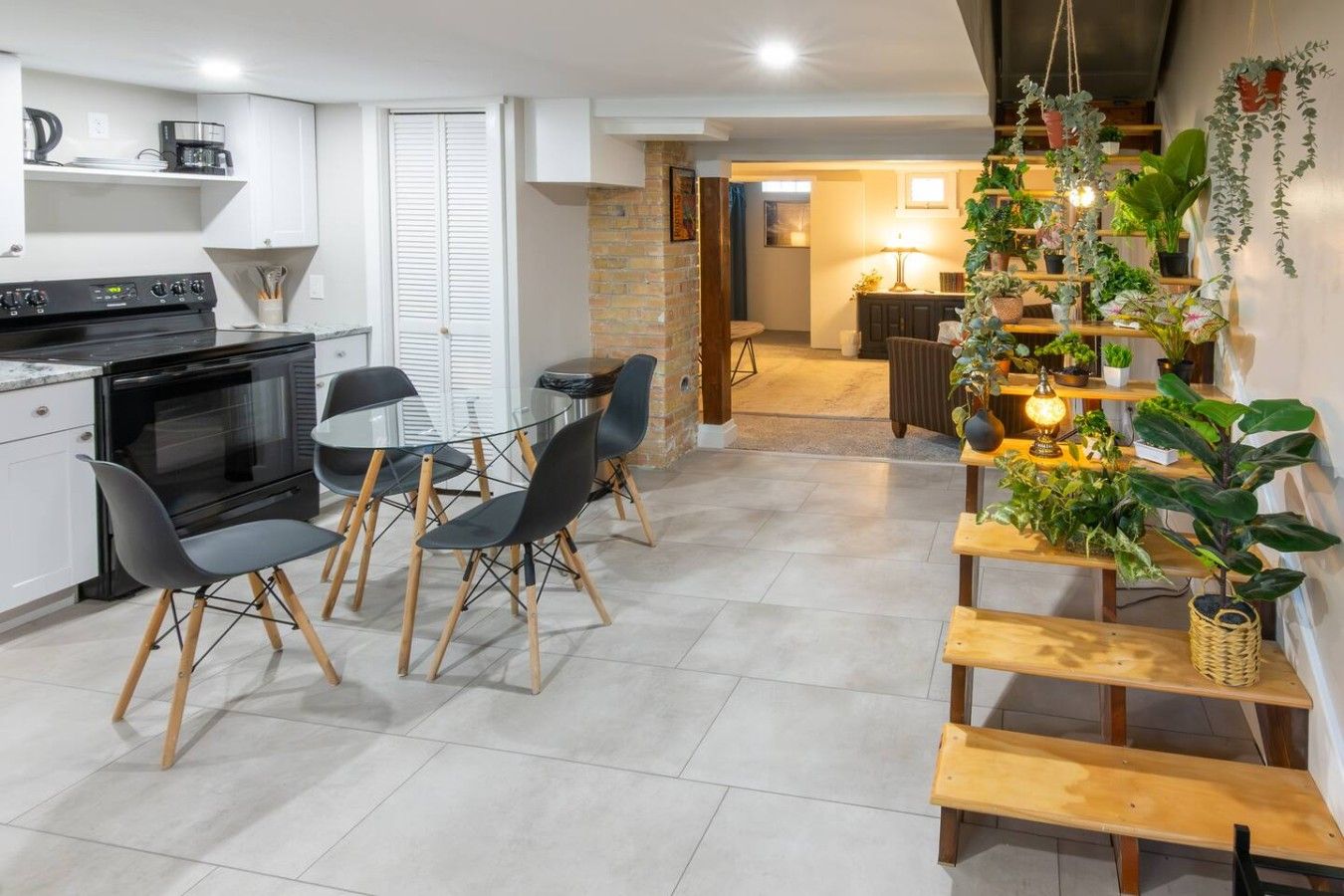 Une cuisine moderne dotée d’un four encastré, de chaises de salle à manger et d’un escalier agrémenté de plantes en pot.