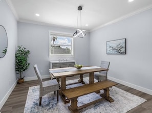 A dining area with a wooden table, four chairs, a bench, a hanging light fixture, a window with a view, a potted plant, and a framed picture on the wall. - Waterfront Home w/ Pool and Kayaks near Beaches (Hernando Beach)