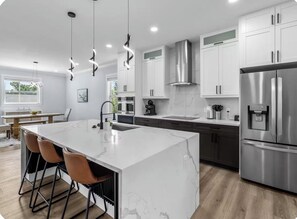 A modern kitchen with a large island, stainless steel appliances, and pendant lighting. - Waterfront Home w/ Pool and Kayaks near Beaches (Hernando Beach)