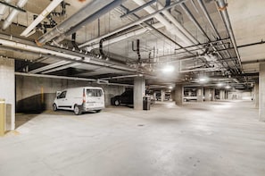 Eine mehrgeschossige Tiefgarage mit Betonböden und darüber verlaufenden Rohren.