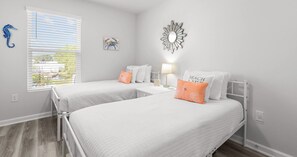 A bedroom with two beds, a window with blinds, a wall-mounted mirror, and a seahorse decoration. - 3BR Coastal Home in Lost Bay (Orange Beach)