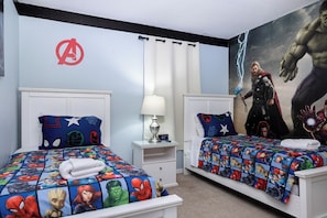 A bedroom with two beds, each with superhero-themed bedding, a wall clock, and a large superhero mural. - 5-Bedroom Near Disney / Free Pool Heat & Spa / Game Room (Clermont)