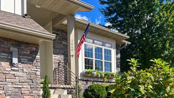 A residential house with a stone facade, a front porch, and a flag.
