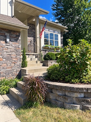 A residential house with a stone facade, a front porch, and a flag.