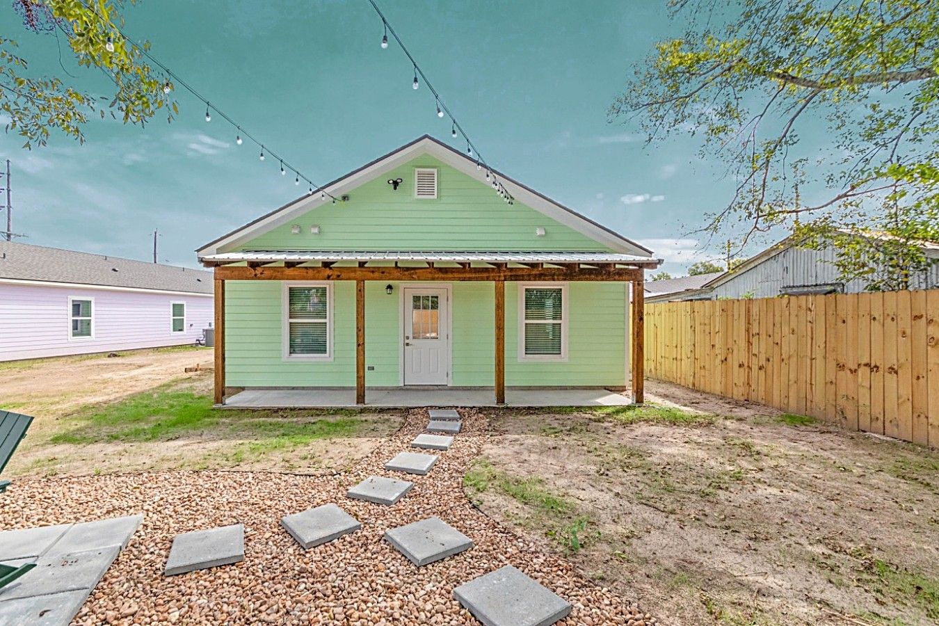 A single-story house with a porch, a front door, and a small front yard with stepping stones.