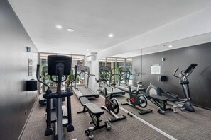 A modern gym with various exercise equipment, including treadmills, stationary bikes, and weight machines. - Elegant 2BR Escape with City Views | Brisbane CBD (Brisbane City)