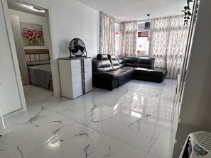 A living room with a sectional sofa, a white cabinet, and a fan. - San Eugenio Fantastic New 4 bedrooms wifi free (Costa Adeje)