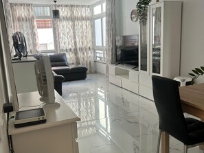 A modern living room with a flat-screen TV, a dining area with a wooden table, and a seating area with a sofa and chairs. - San Eugenio Fantastic New 4 bedrooms wifi free (Costa Adeje)