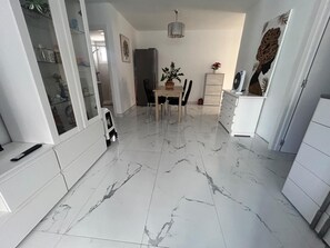 A modern kitchen with a marble floor, white cabinetry, a dining table with chairs, and a potted plant. - San Eugenio Fantastic New 4 bedrooms wifi free (Costa Adeje)