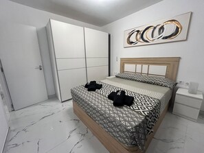 Et soveværelse med seng, garderobeskab, natbord og et billede på væggen.