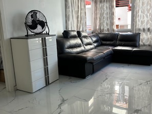 A modern living room with a sectional sofa, a white cabinet, and a floor fan. - San Eugenio Fantastic New 4 bedrooms wifi free (Costa Adeje)