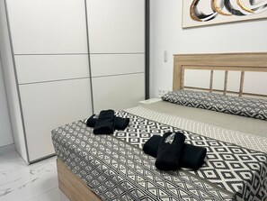 Een net opgemaakt bed met beddengoed met een patroon, een houten hoofdbord en een kunstwerk aan de muur.