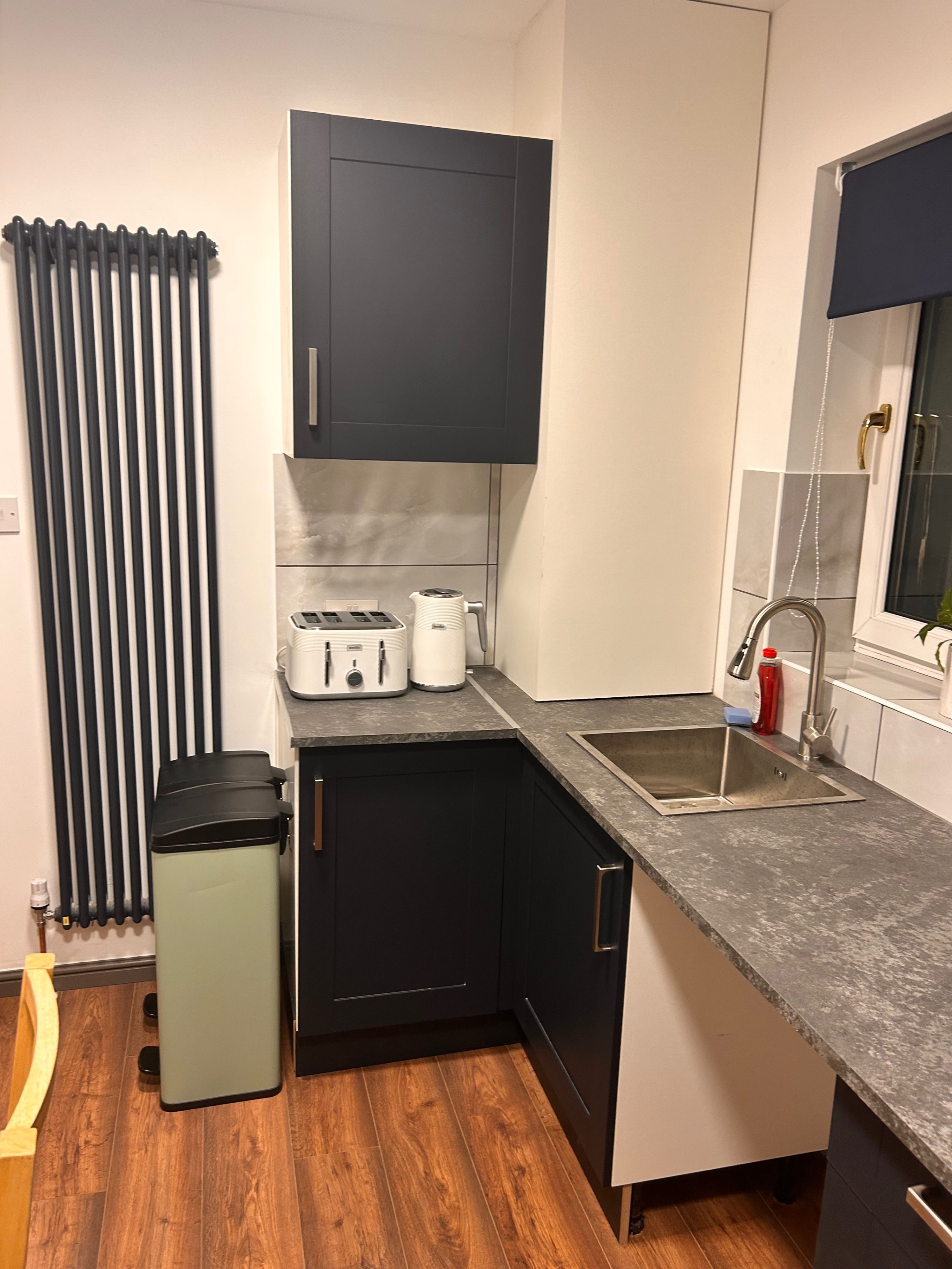 A compact kitchen with a built-in dishwasher, a sink, and a window with a view.