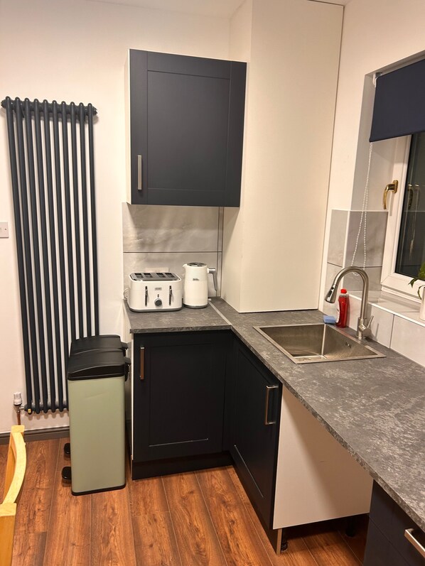 Una cocina compacta con lavavajillas integrado, un lavamanos y una ventana con vistas.