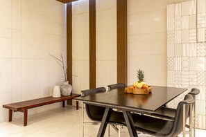 A dining area with a rectangular table, black chairs, a wooden bench, and a fruit bowl on the table. - OriVista 2BR Private Pool Villa w/ Rice FieldView (Ubud)