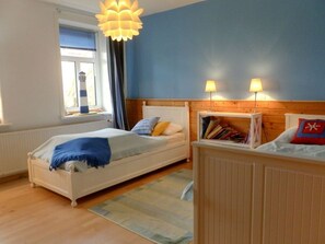 A bedroom with two beds, a window with curtains, a wooden headboard, and a bookshelf. - Holiday Apartment With 2 Bedrooms (Oldsum)