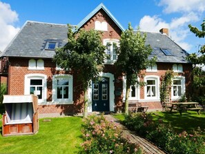 A two-story brick house with a gabled roof, a front door, and a small porch with a bench. - Holiday Apartment With 2 Bedrooms (Oldsum)