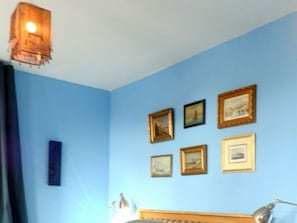 A room with a blue wall, a wooden headboard, and several framed pictures. - Holiday Apartment With 2 Bedrooms (Oldsum)